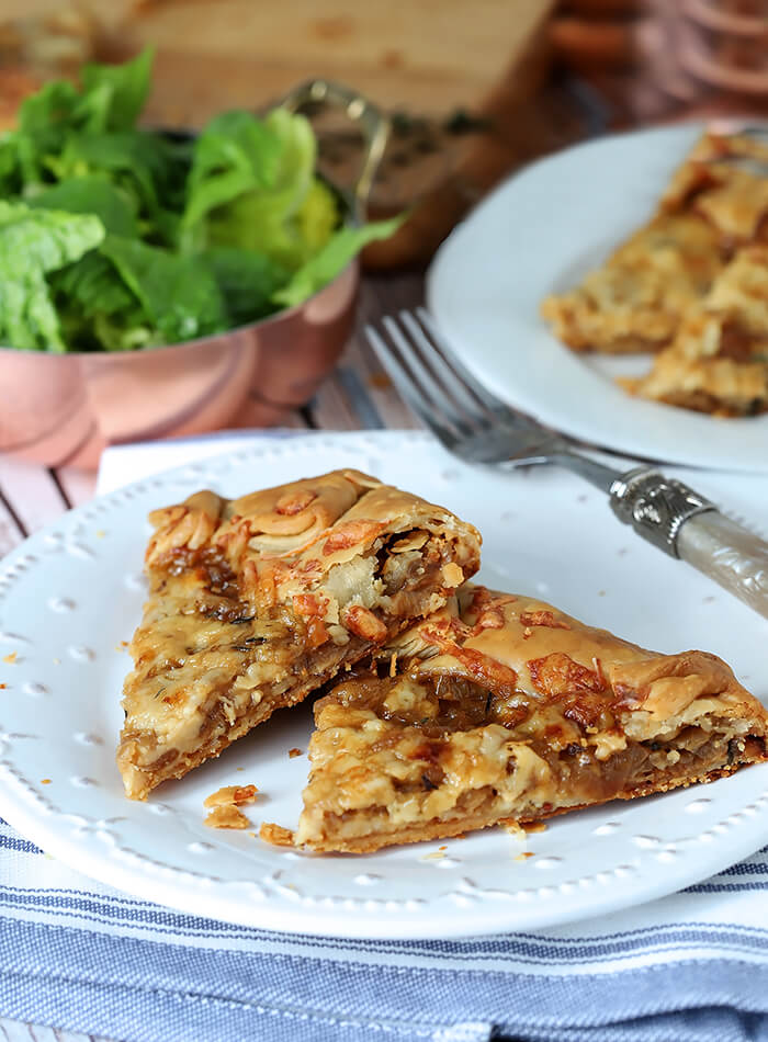 French Onion Galette Slices on a White Plate Served with a Salad