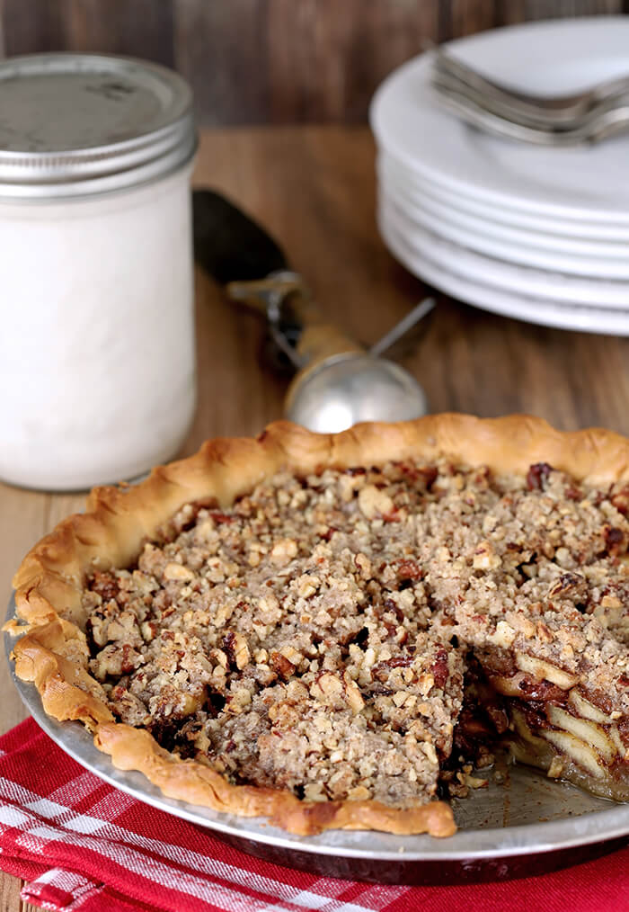 Bourbon Caramel Apple Pie with Pecan Crumble in a Metal Pie Plate with One Slice Missing