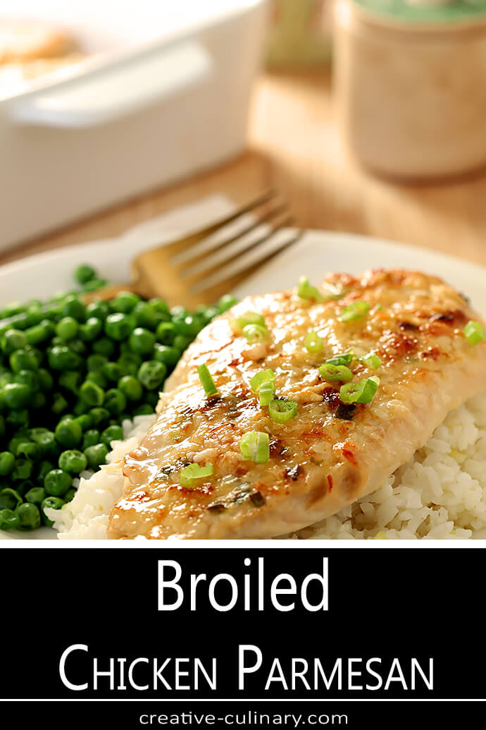 Serving of Broiled Chicken Parmesan on a White Plate with a Gold Fork and Green Peas on the Side