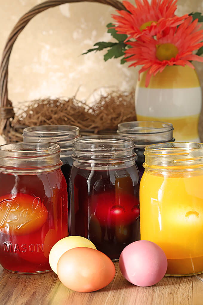 Organically Dyed Easter Eggs Soaking in Jars of Colored Liquid from Vegetables and Spices