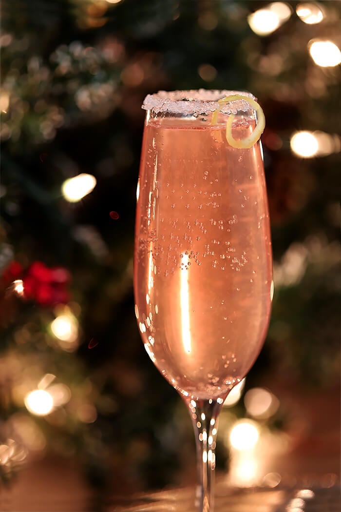 French 77 Pink Champagne Cocktail Garnished with a Sugar Rim and Lemon Peel