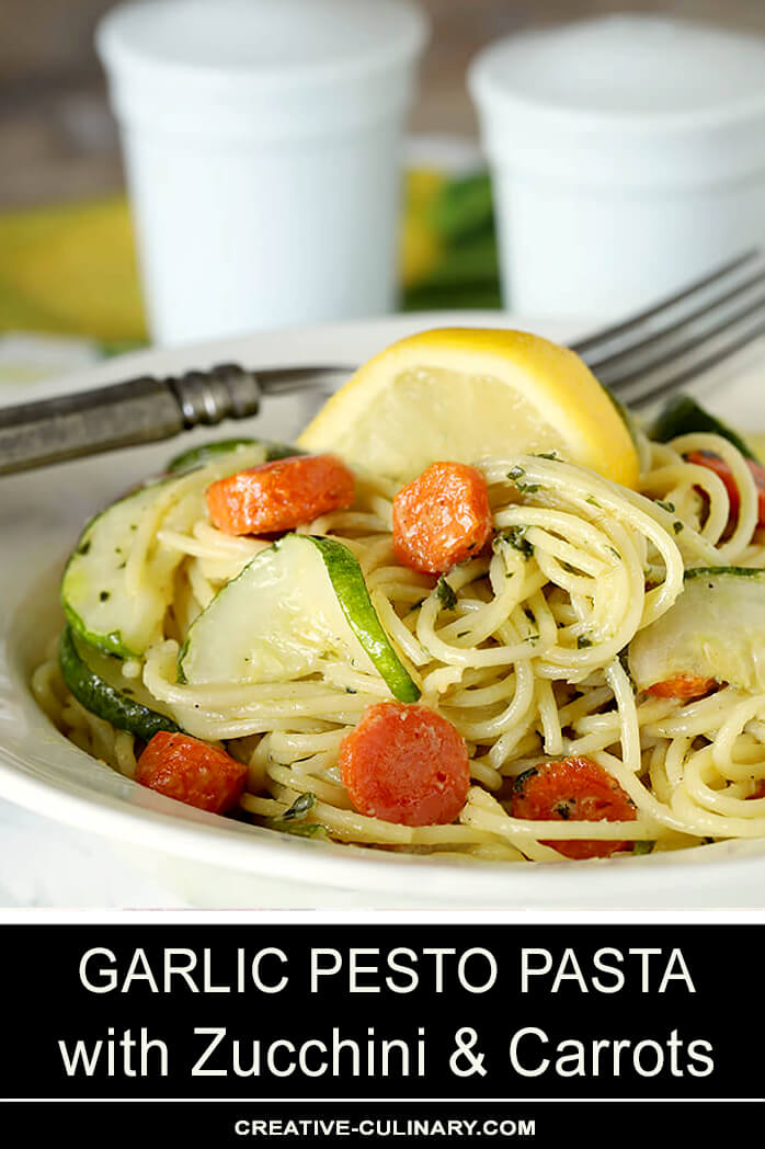 Garlic Pesto Pasta with Carrots & Zucchini Served on a White Plate with Lemon Garnish