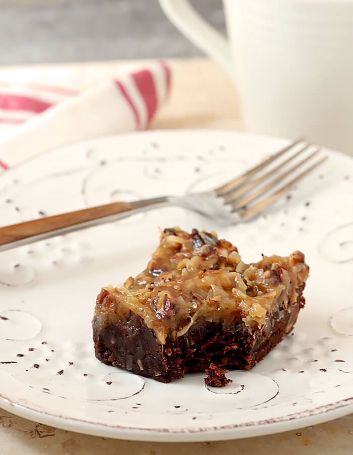 One German Chocolate Brownies with a Bite Removed Served on a White Plate