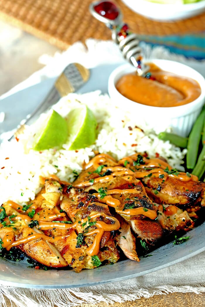 Grilled Chicken Satay with Peanut Sauce on Plate with Rice Garnished with Lime Wedges