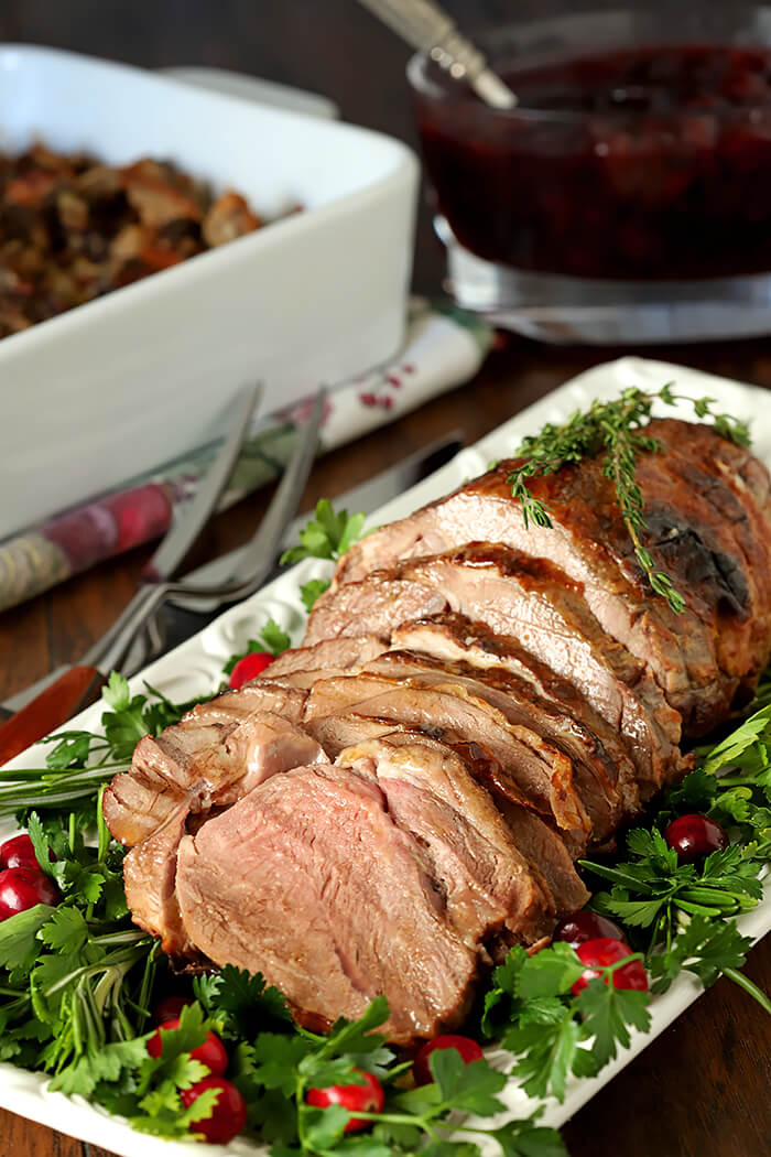 Honey Roasted Lamb with Honey and Thyme on White Serving Plate with Lettuce and Cranberry Garnish