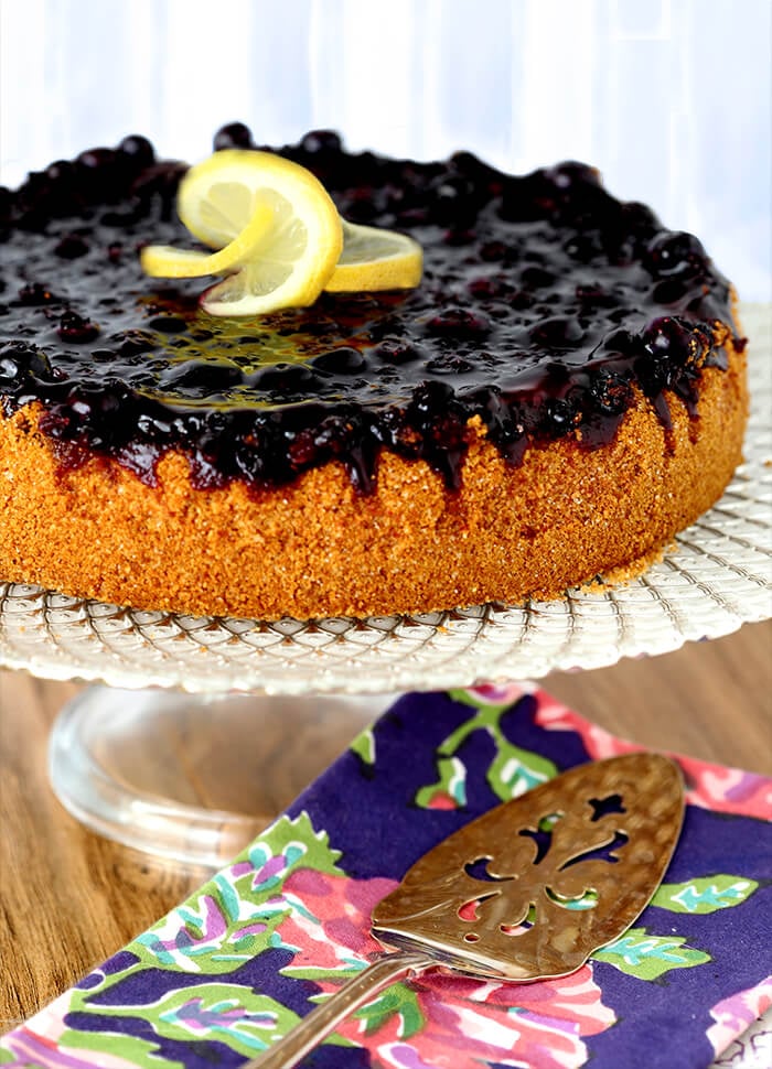 Whole Lemon Blueberry Cheescake with a Blueberry Topping with Lemon Garnish on a White Cakeplate