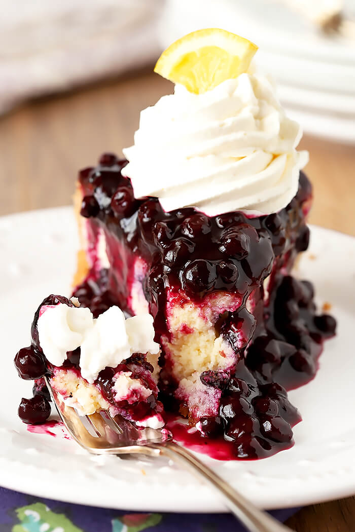 Single Slice of Lemon Blueberry Cheescake with a Blueberry Topping Served with Whipped Cream Topping and Lemon Quarter