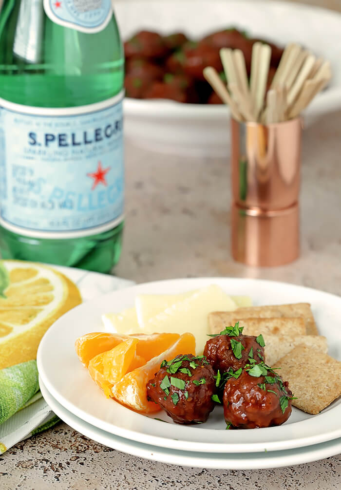 Serving of Meatballs with a Grape Jelly and Chili Sauce on a White Plate with Oranges, Cheese, and Crackers