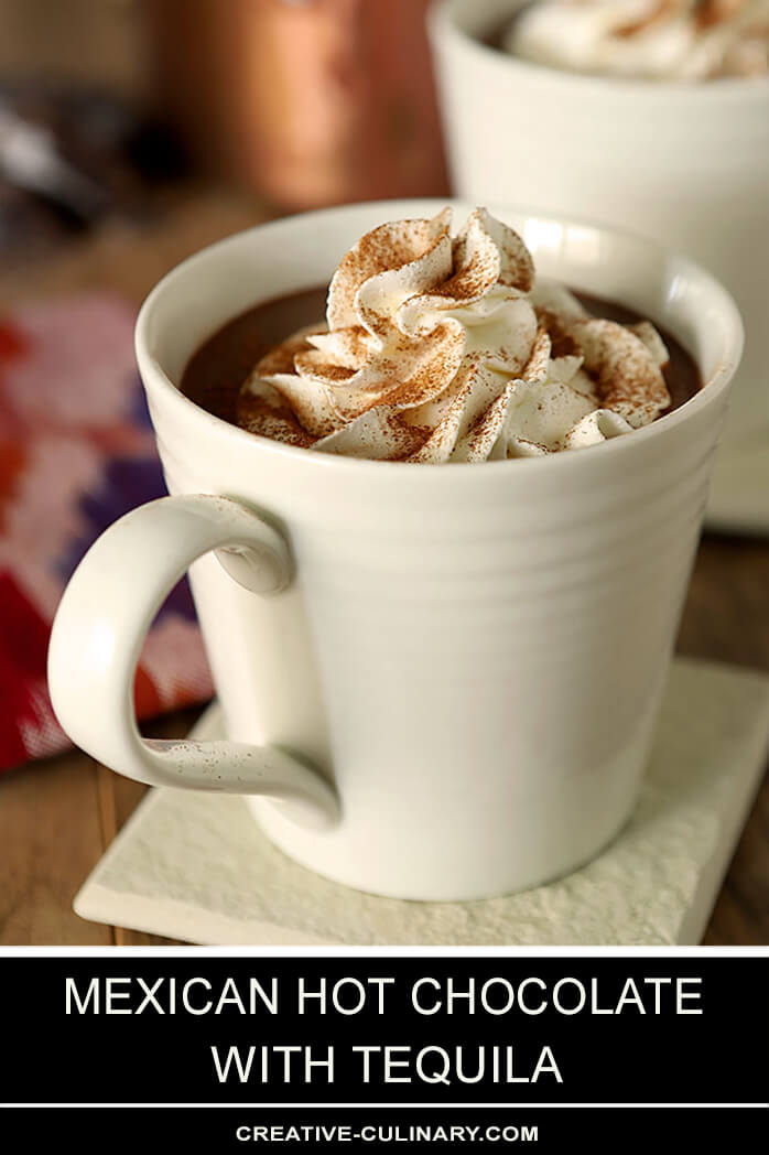 Mexican Hot Chocolate with Tequila Served in a White Mug with Whipped Cream on Top and Dusted with Cinnamon