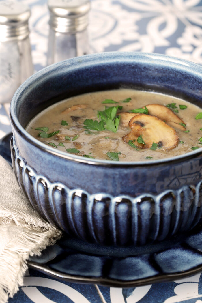 Homemade Cream of Mushroom Soup in a blue bowl filled with a rich creamy mushroom soup.