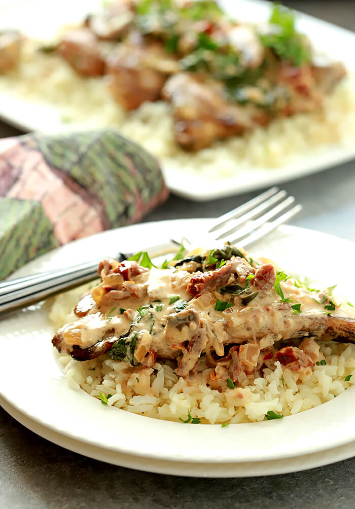 Creamy Mushroom Sauce with Sun-Dried Tomatoes and Spinach Served over Chicken and Garnished with Parsley