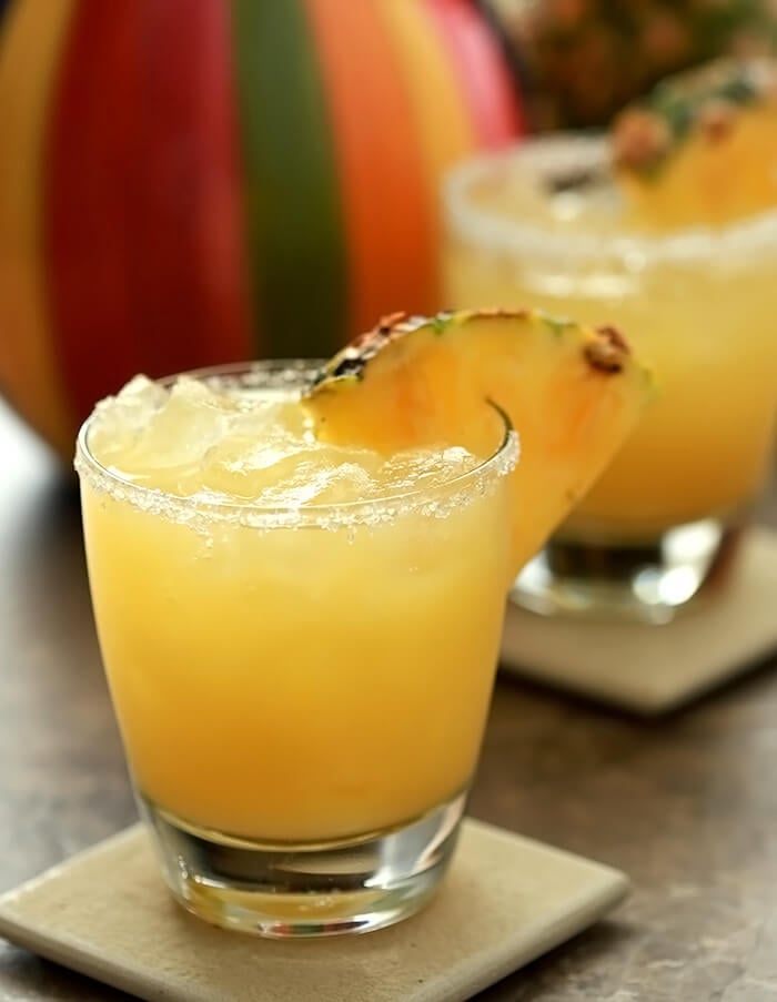 Fresh Pineapple Margarita Cocktails garnished with wedges of pineapple.