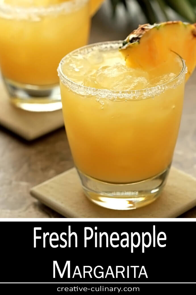 Fresh Pineapple Margarita in a lowball glass with a salt/sugar rim and garnished with a pineapple wedge.