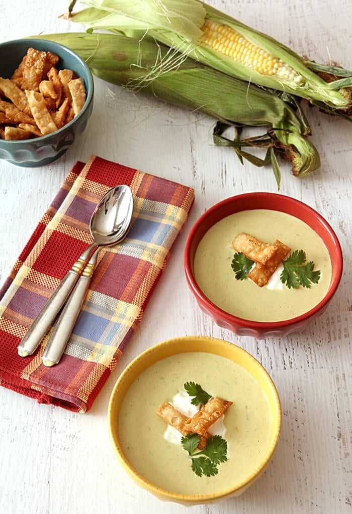 Two Bowls of Roasted Poblano Pepper and Corn Soup in Yellow Bowl Garnished with Tortilla Strips