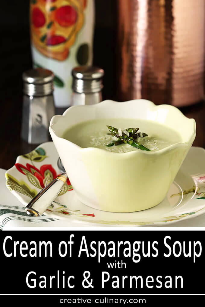 Cream of Asparagus Soup Served in a White and Yellow Bowl with both Asparagus Spear and Parmesan Garnish